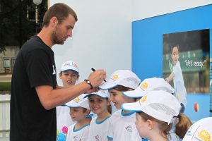Mardy Fish signs the caps of young fans.