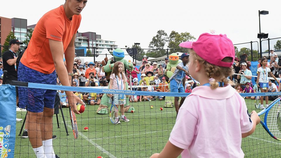 Bernard Tomic helps a young fan with her forehand. Picture: GETTY IMAGES